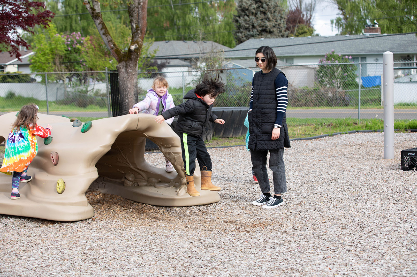 Children playing on a playground being supervised by an adult